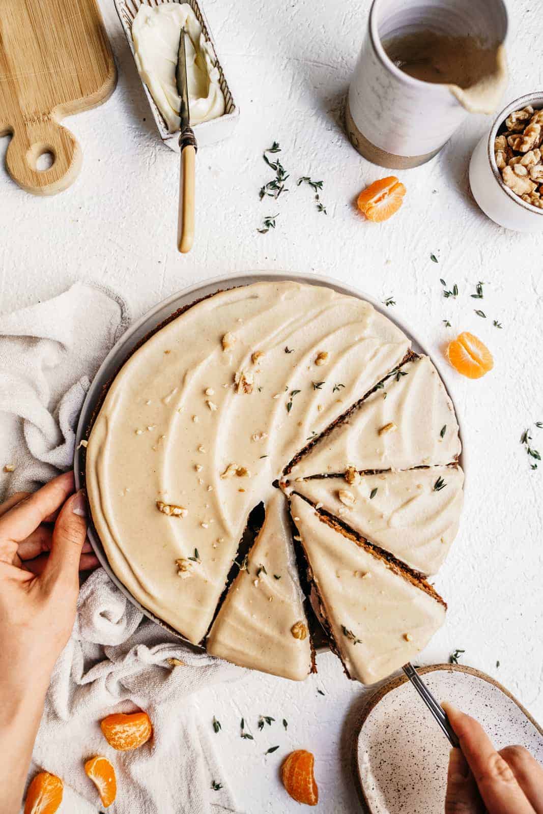 Vegan carrot cake sitting on countertop with slices out of it ready to be devoured. 