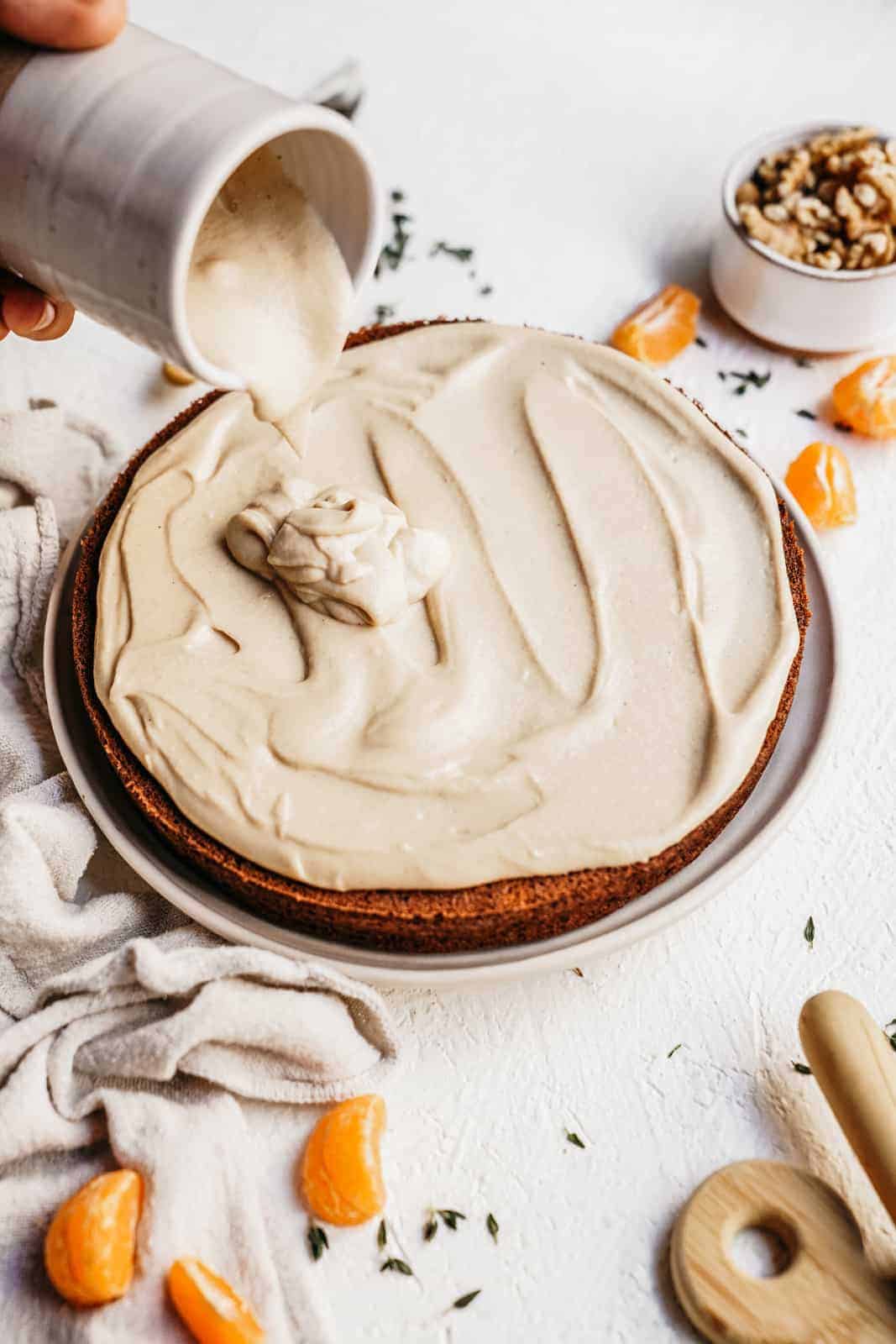 Cashew icing being poured on the Vegan Carrot Cake recipe.