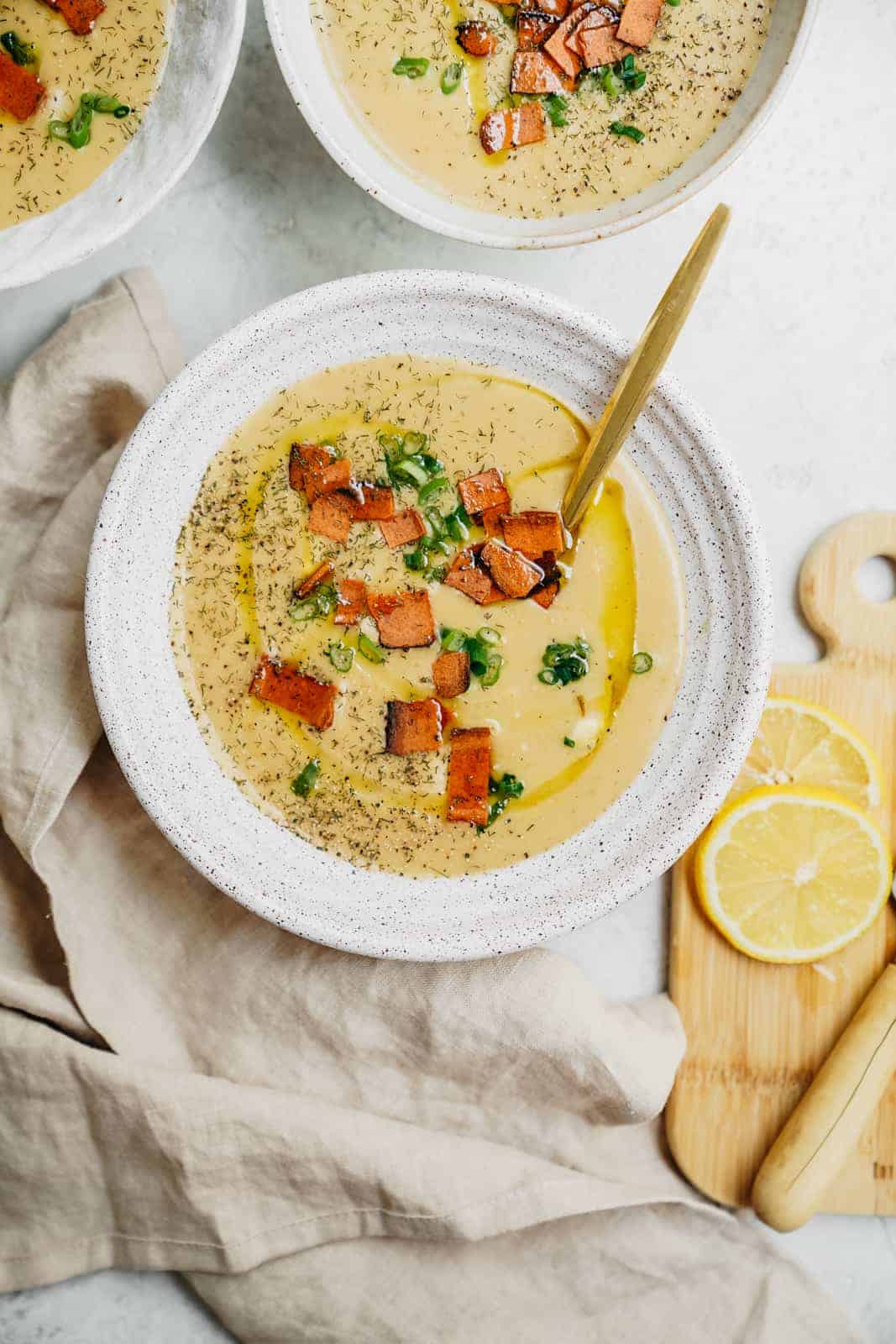 Bowls of potato soup with slices of lemon on the side as a garnish.