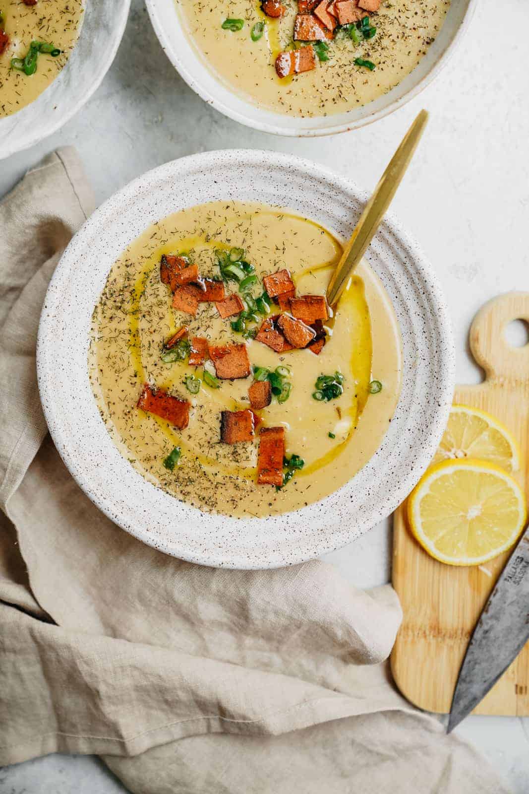 Bowls of creamy Vegan Potato Soup on countertop ready to be eaten with a sprinkle of vegan bacon.