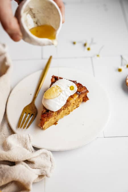 Slice of banana bread cake on plate with honey being drizzled on top