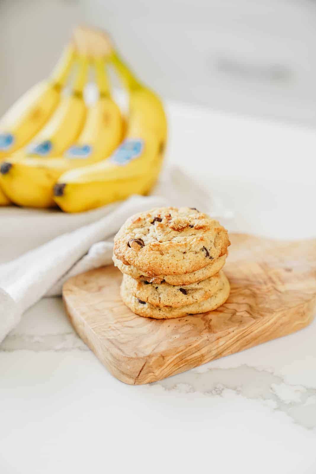 Banana chocolate chip cookies on counter with bananas