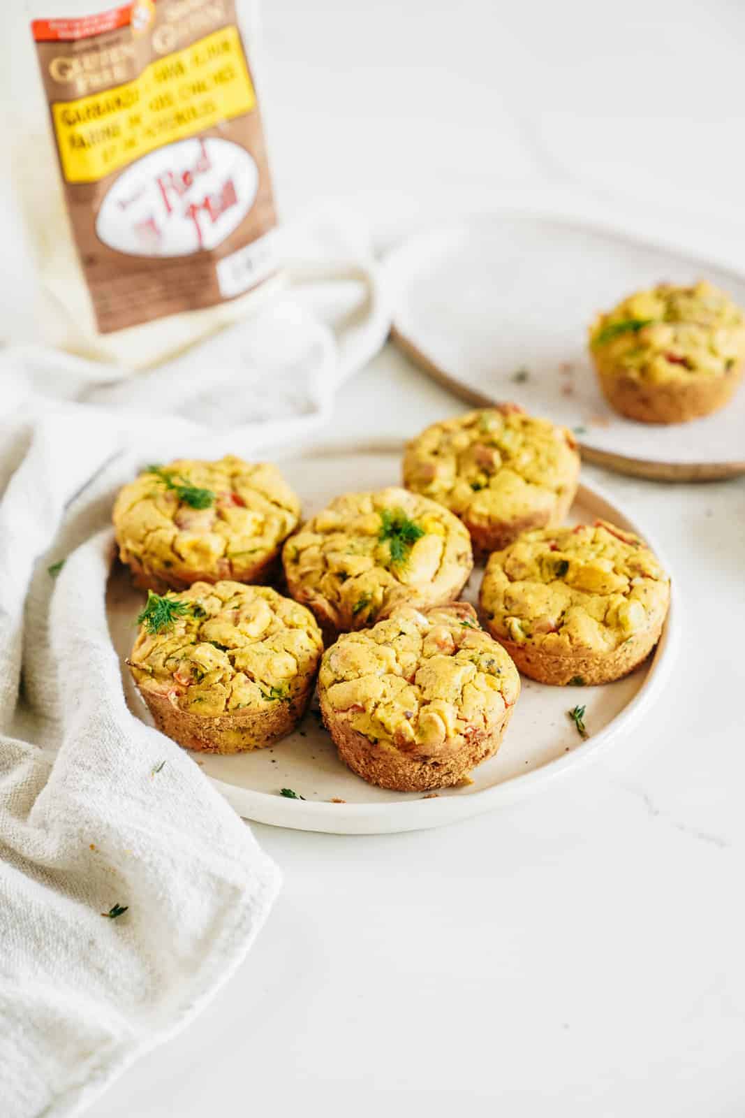 Vegan Chickpea Flour Muffins sitting on a plate with Bob's Red Mill flour in the background.