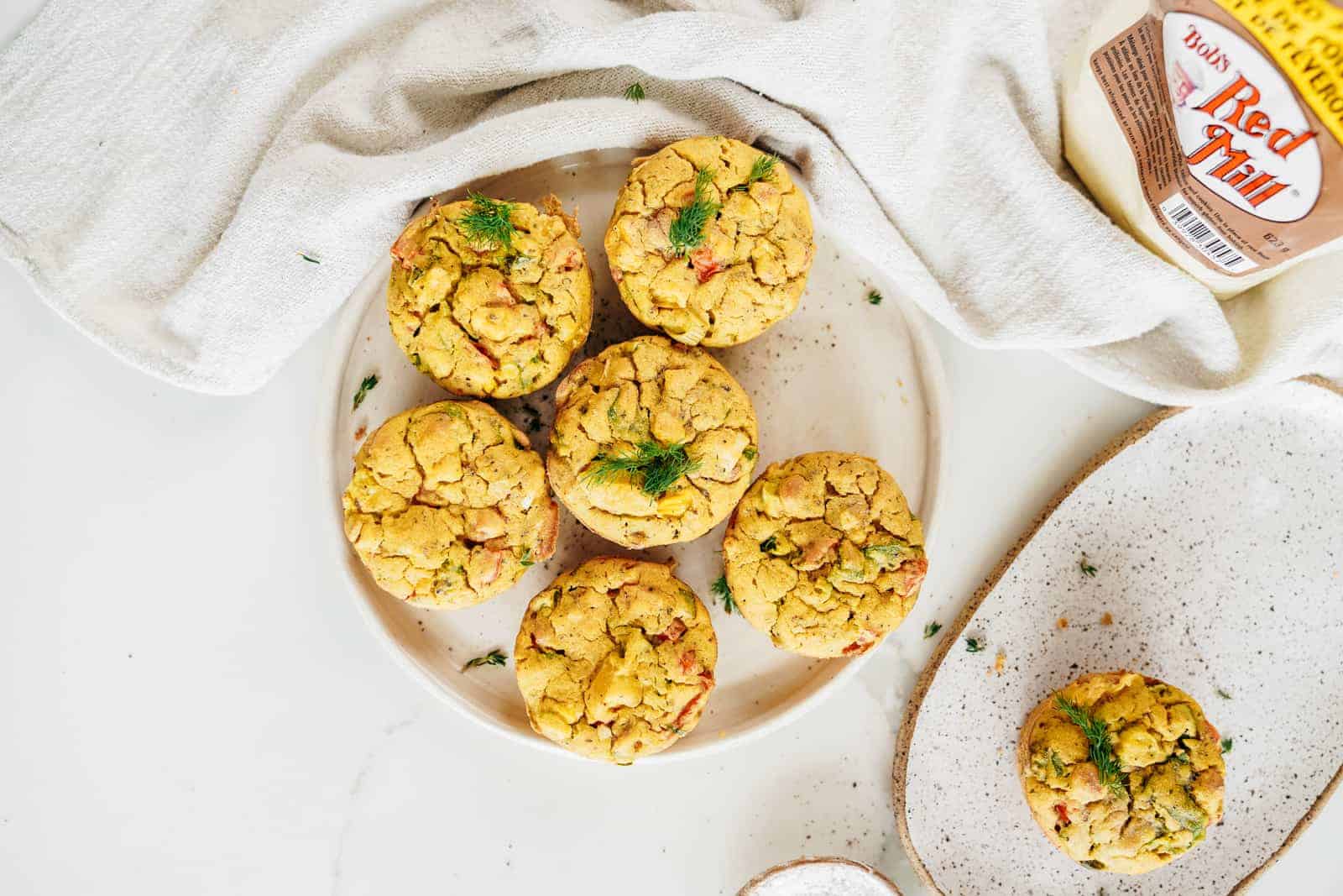 Vegan Chickpea Flour Muffins sitting on a plate with Bob's Red Mill flour in the background.