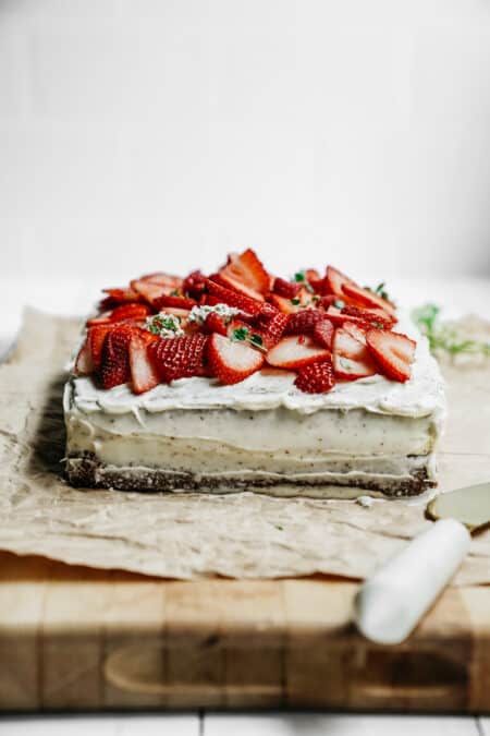 Side angle of a Honey Cake topped with fresh cut strawberries.