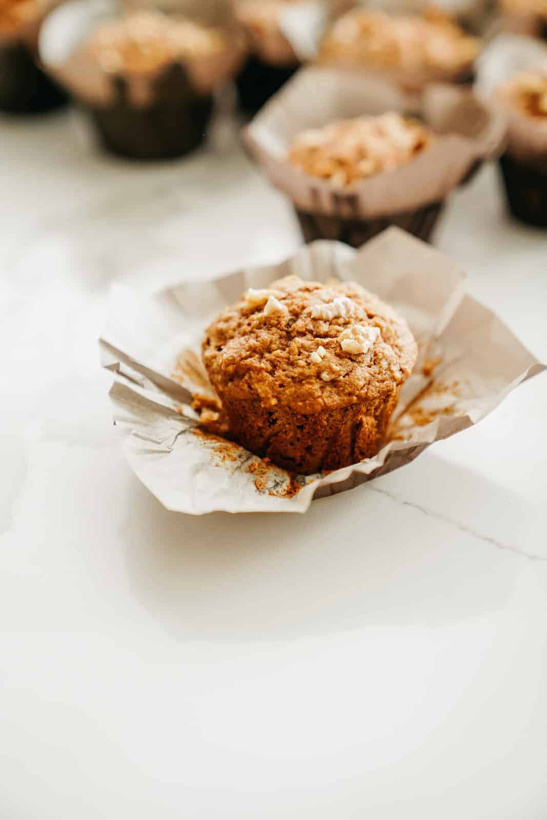 Vegan Apple Cinnamon Muffin with muffin wrapper peeled off, ready to eat.