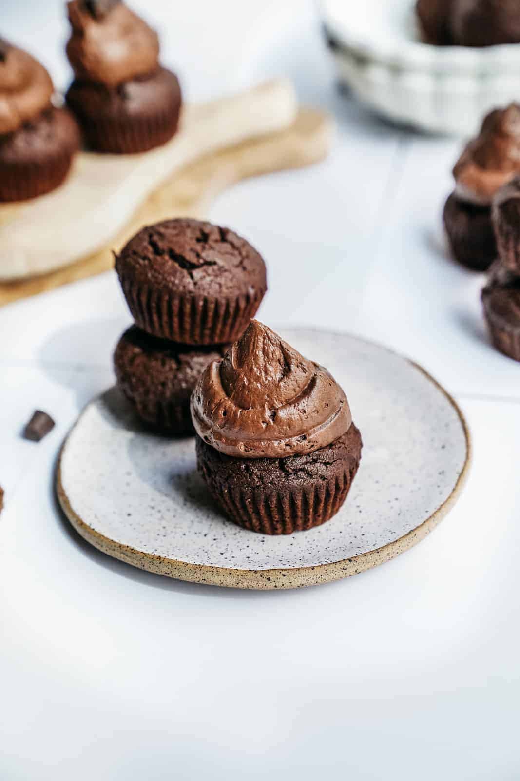 Vegan Brownie Muffins scattered on a plate. Some topped with icing and some naked.