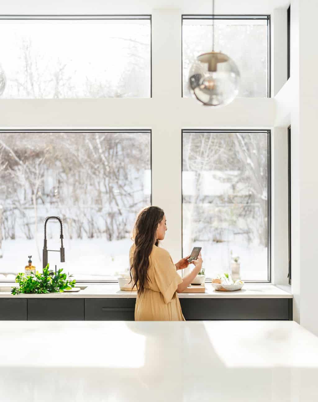 Maria, a food blogger, in a kitchen with gorgeous floor to ceiling windows.