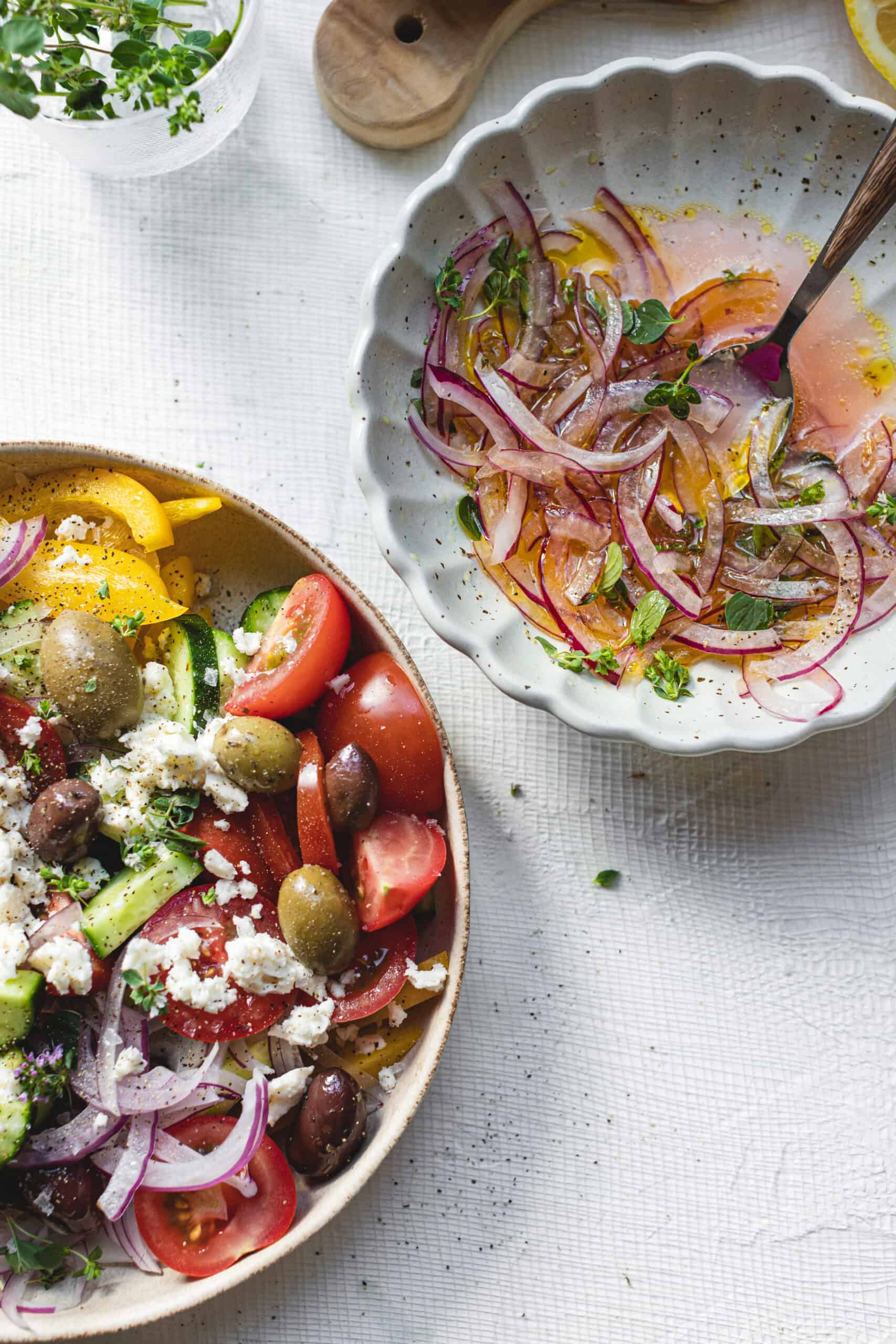 Simple Homemade Greek Salad next to a bowl of pickled onions