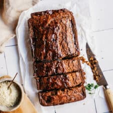 Zucchini Banana Bread on counter with knife, with a few slices cut out of it.