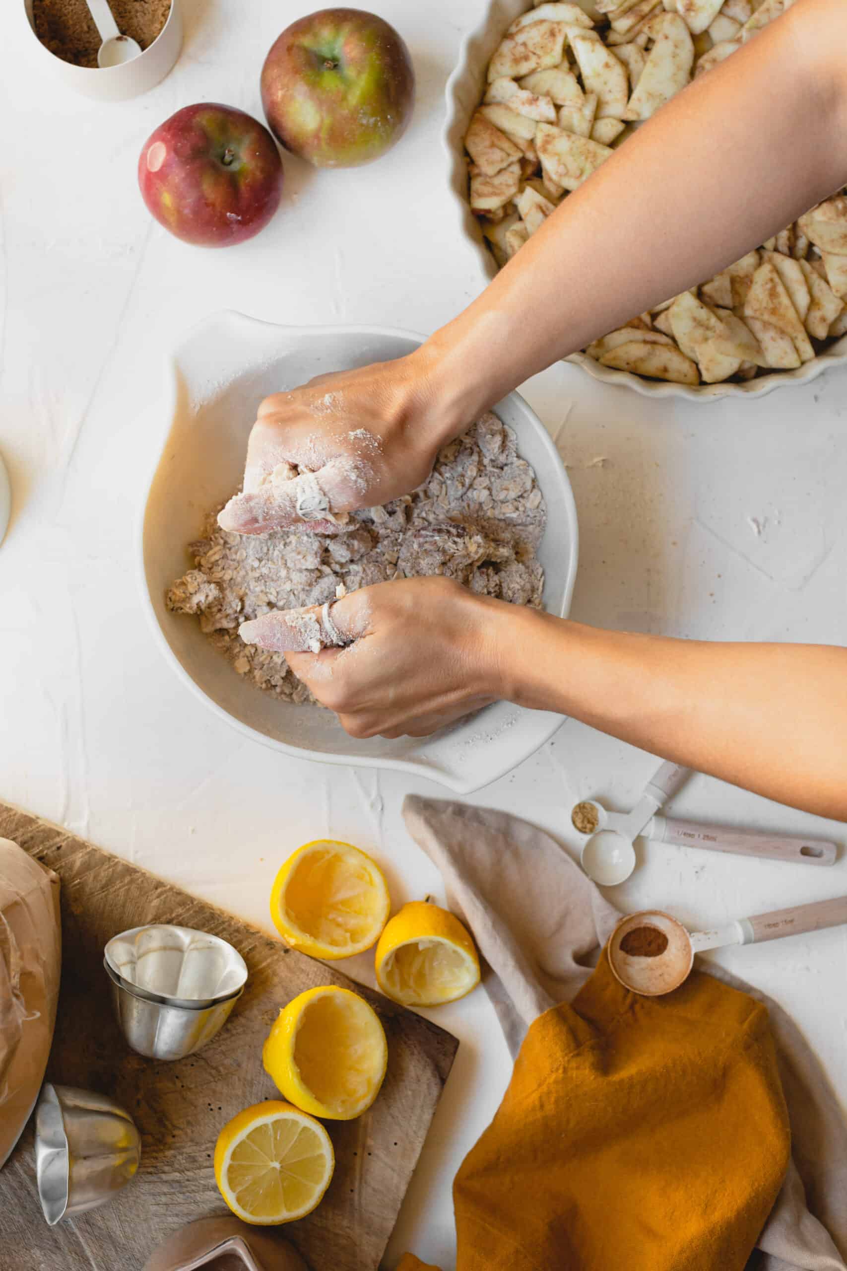 Hands mixing all ingredients together to create the crumble topping for the Vegan Apple Crumble.