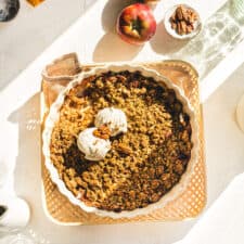 Vegan Apple Crumble with perfect sunlight shining in onto the serving dish with vanilla ice cream.