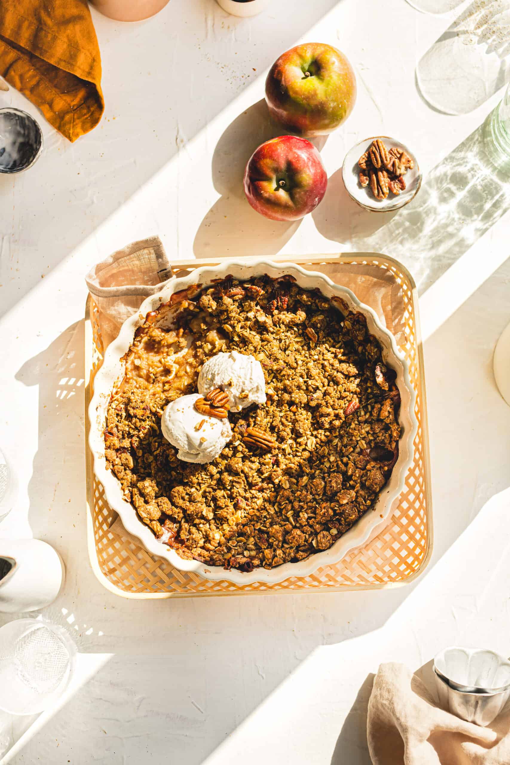 Vegan Apple Crumble with perfect sunlight shining in onto the serving dish with vanilla ice cream.