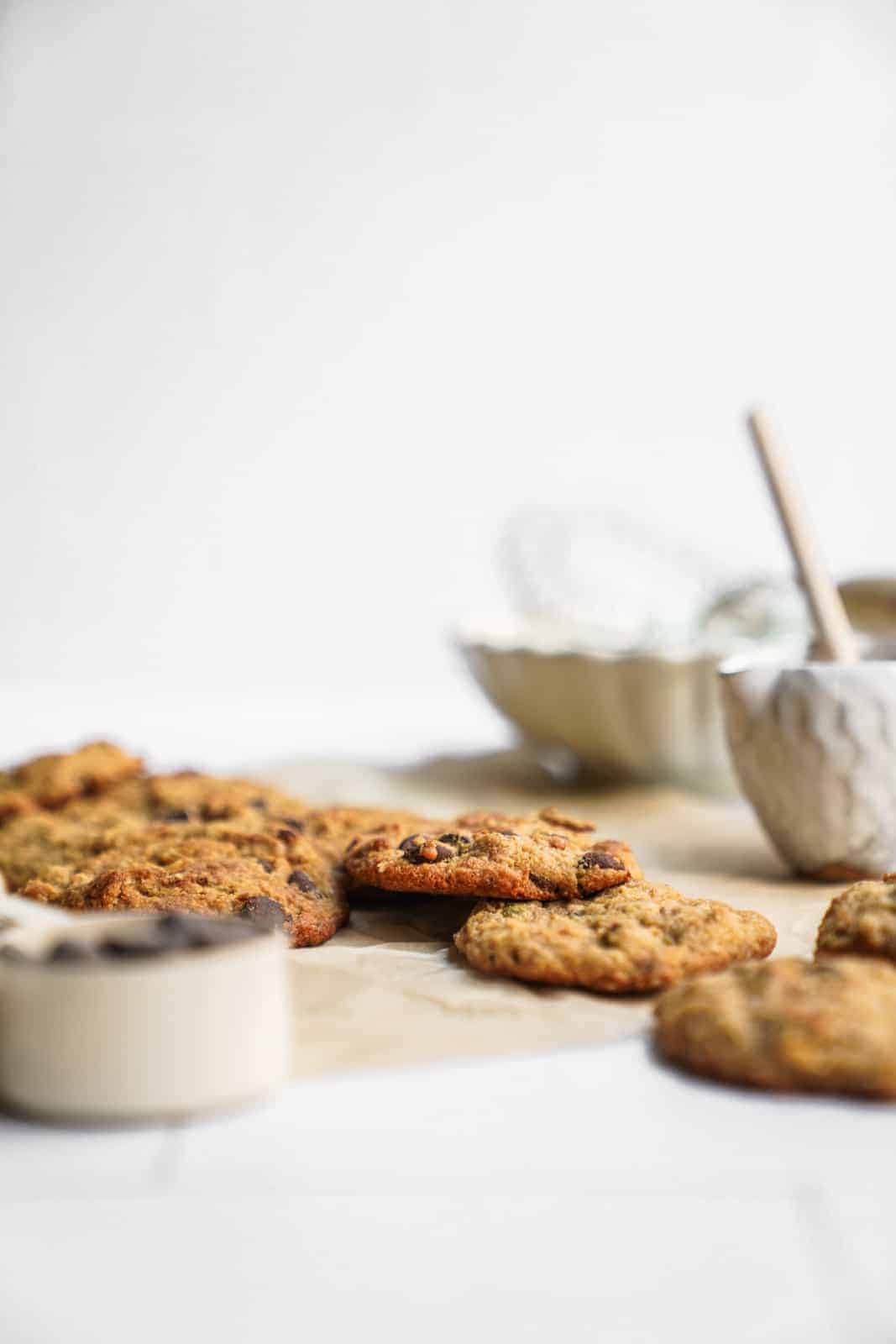 Scatted cookies on countertop surrounded by ingredients.
