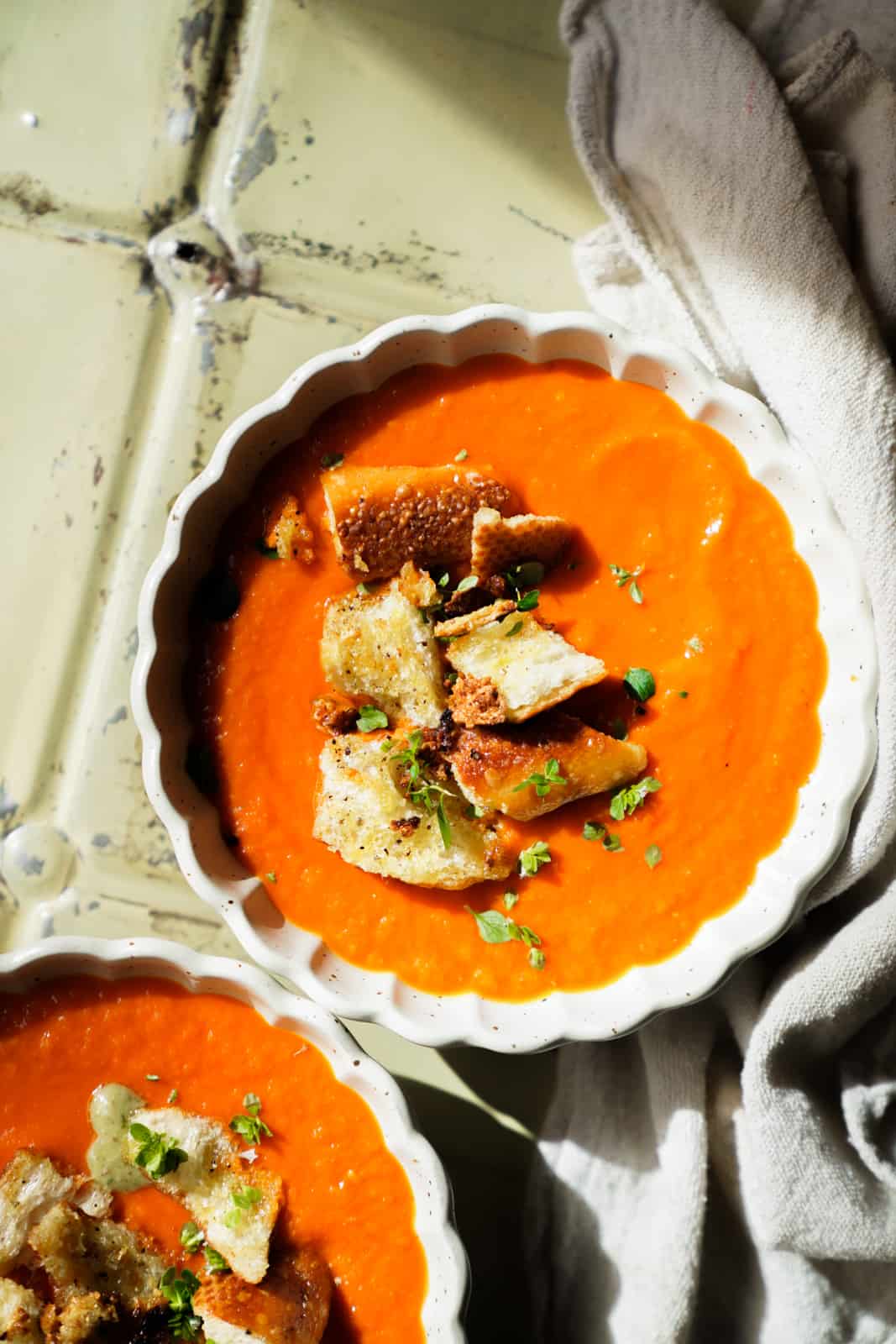 Overhead photo of Roasted Tomato Soup with garlic crotons and basil on top