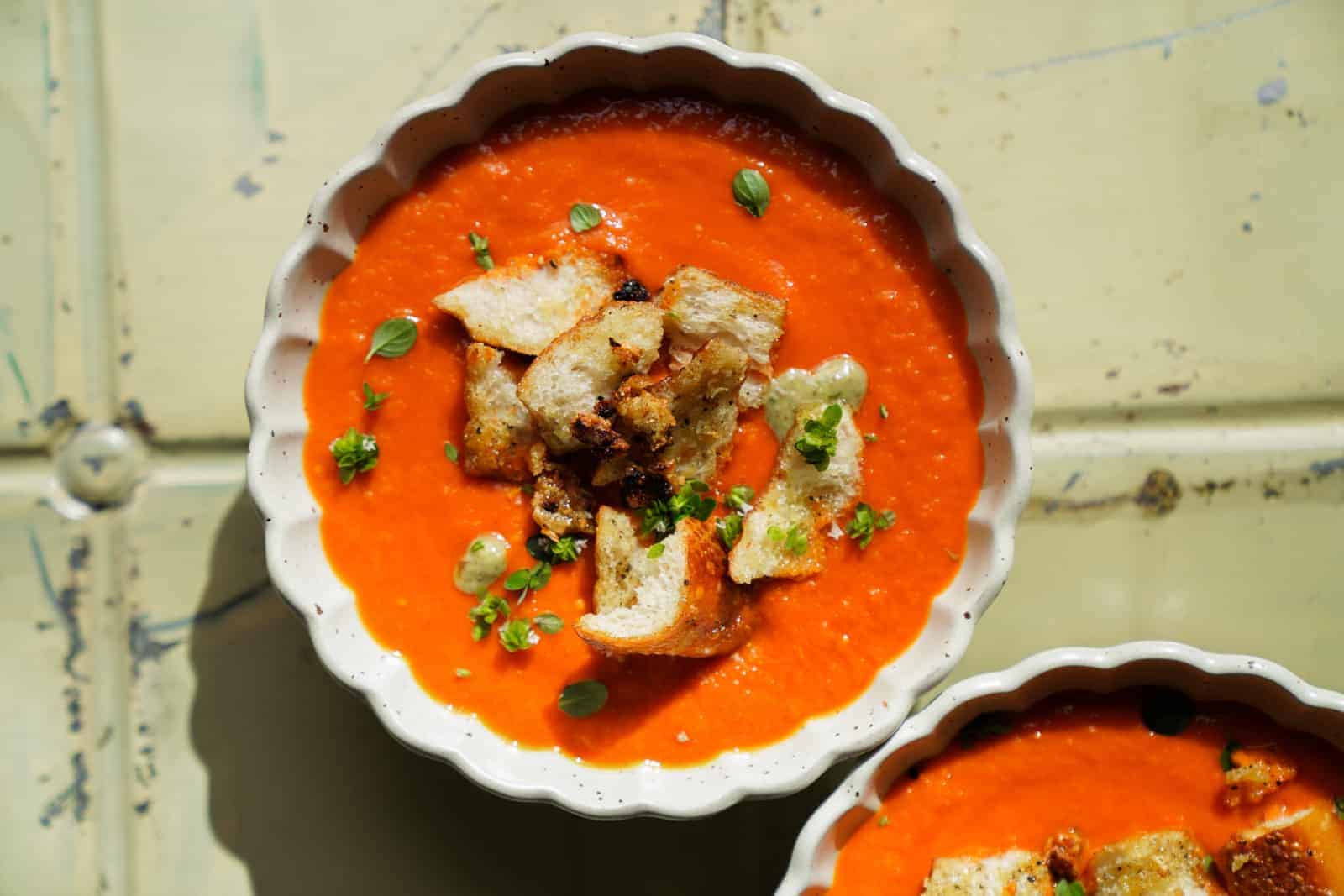 Overhead photo of Roasted Tomato Soup with garlic crotons and basil on top