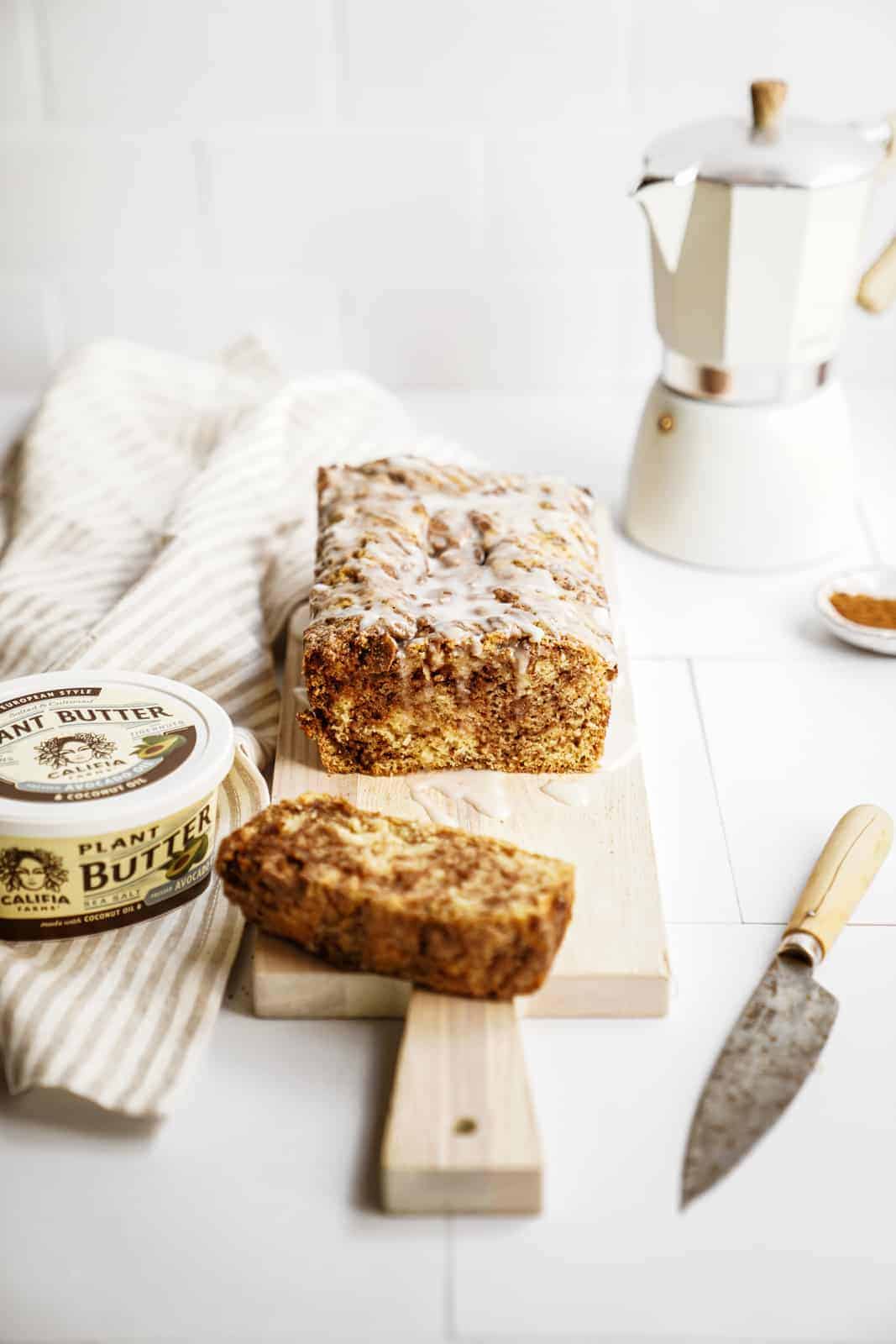 Vegan Cinnamon Bun Bread sliced on cutting board with plant butter beside it