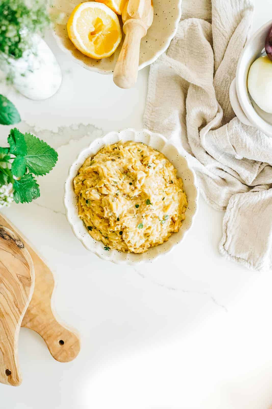 Big Bowl of Vegan Orzo with Creamy Zucchini and Lemon with garnish on a countertop