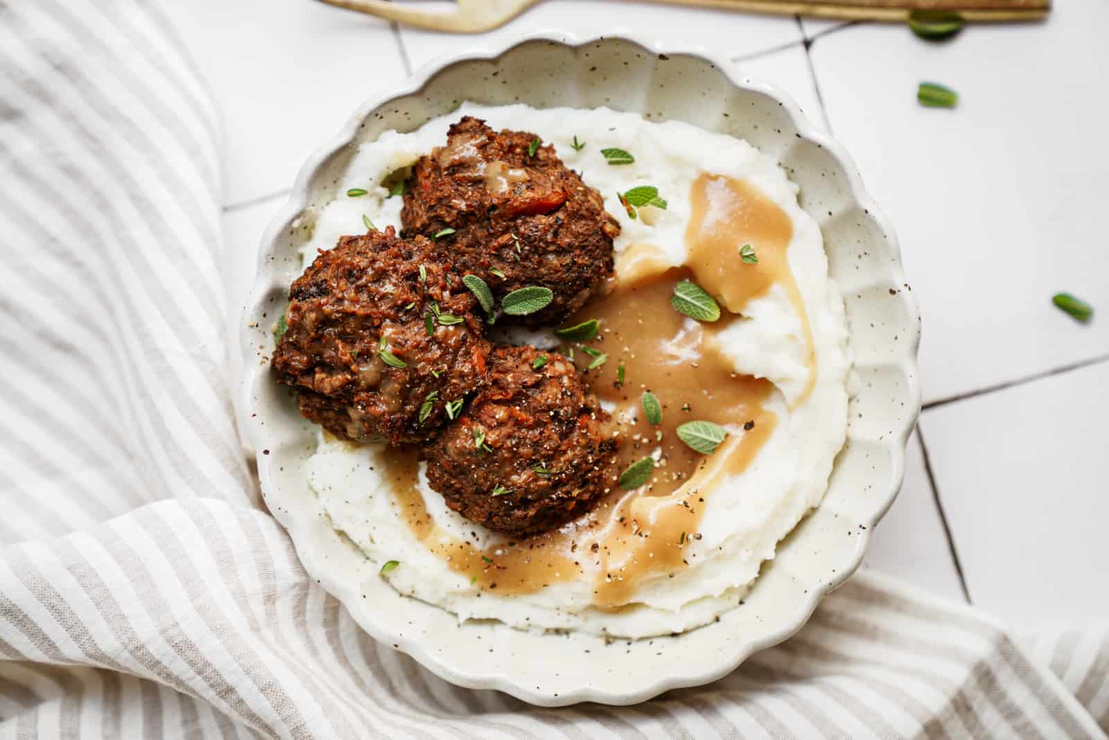 Vegan meatballs with a side of vegan mashed potatoes and gravy on countertop.