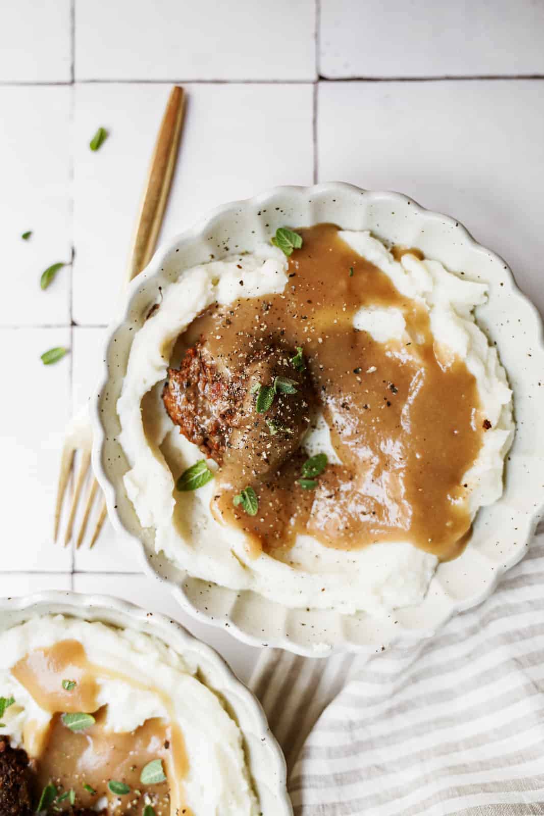 Vegan meatballs with a side of vegan mashed potatoes and gravy on countertop.