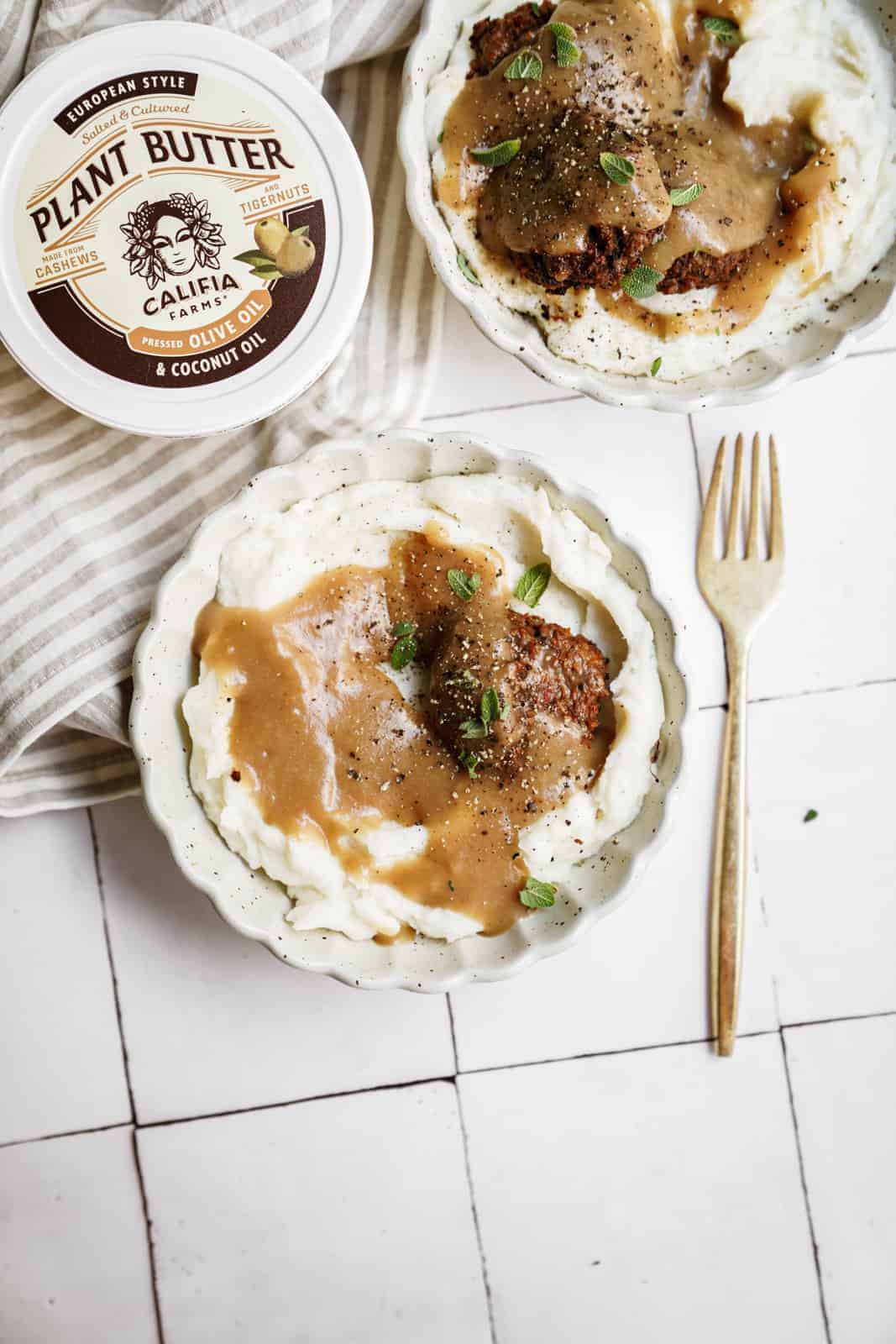 Vegan meatballs with a side of vegan mashed potatoes and gravy on countertop.