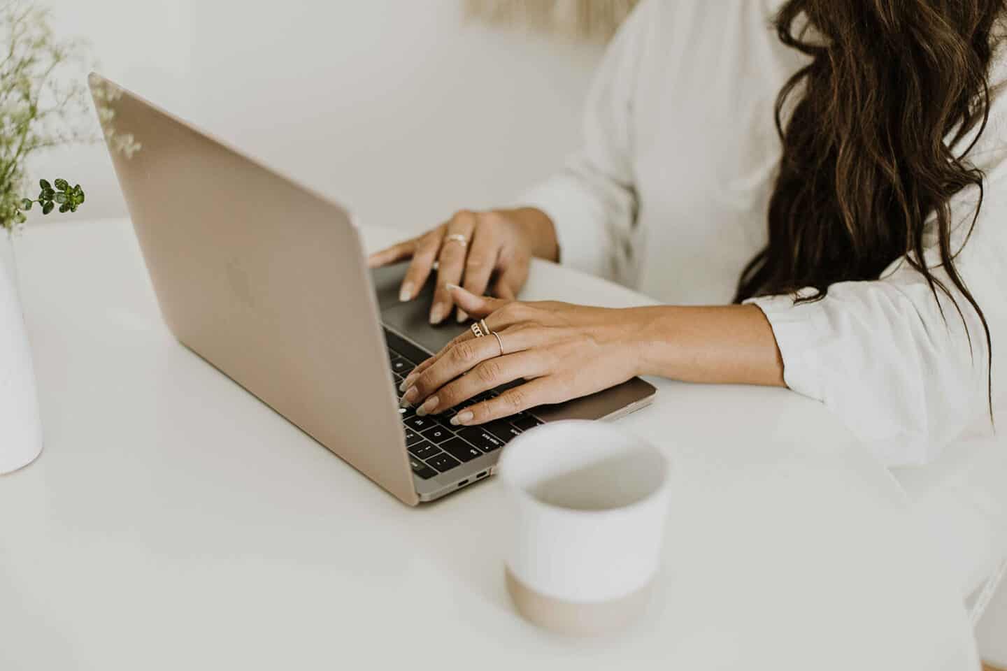 Food blogger on laptop computer with a coffee cup beside her.