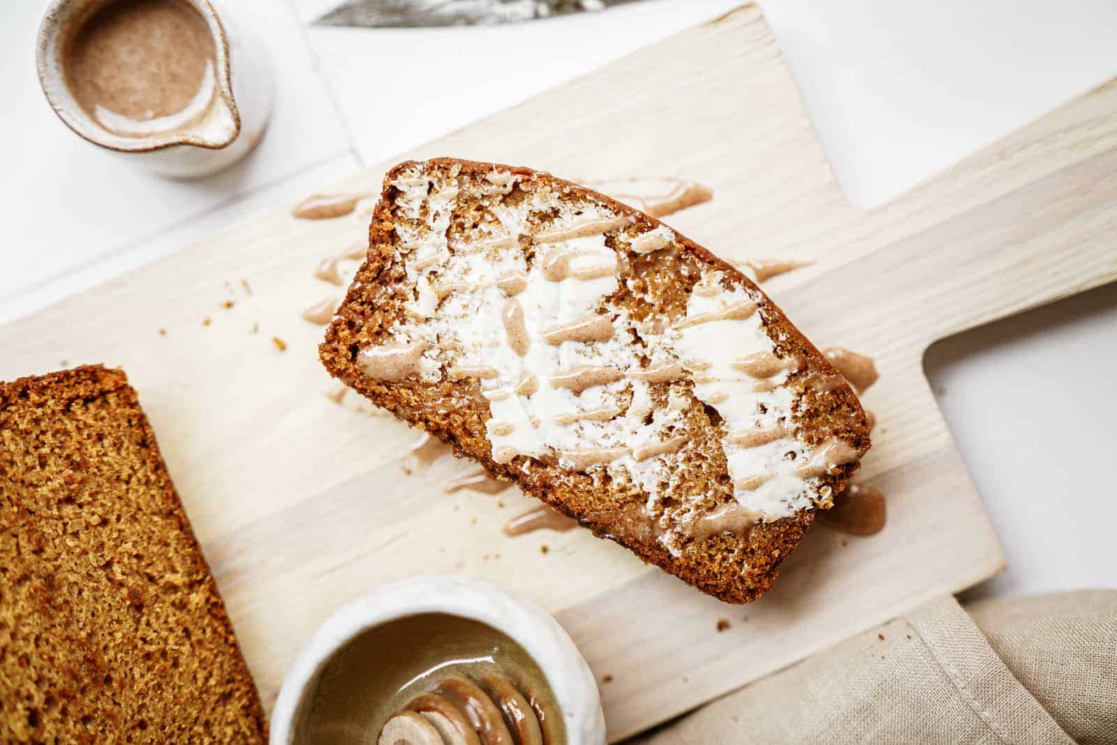 Slice of vegan pumpkin bread buttered on top of cutting board