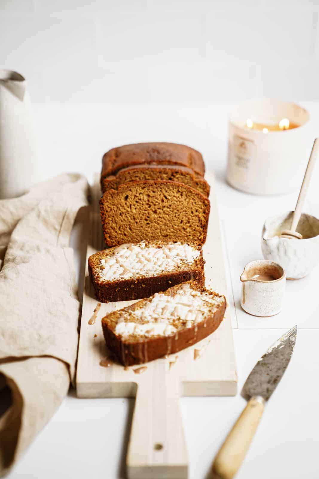 vegan pumpkin bread on cutting board with slices out of it and buttered