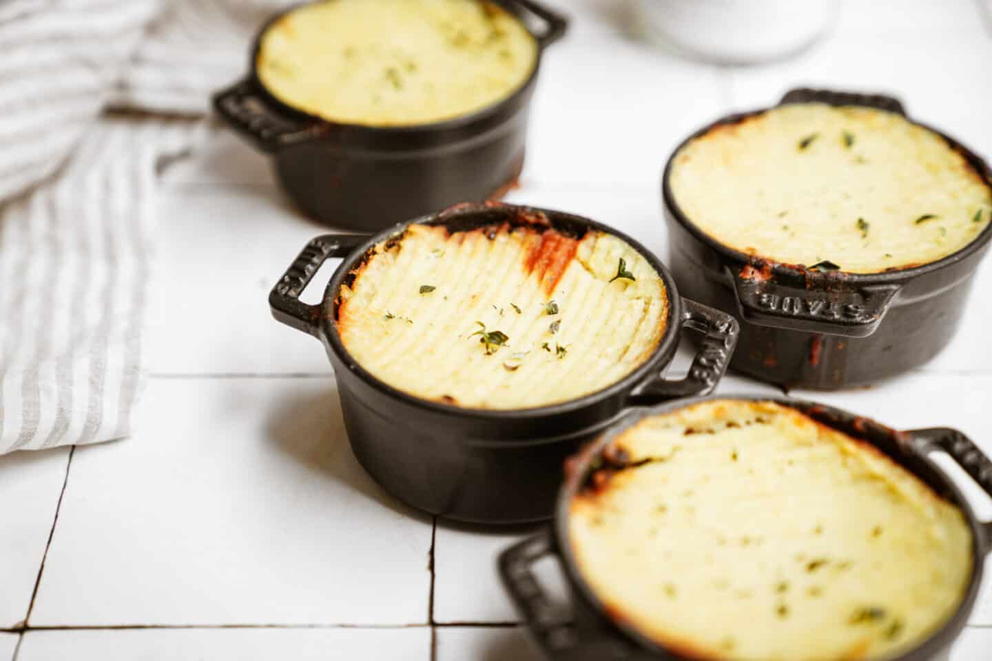 Scattered little Lentil Shepherd's Pie in pots on counter