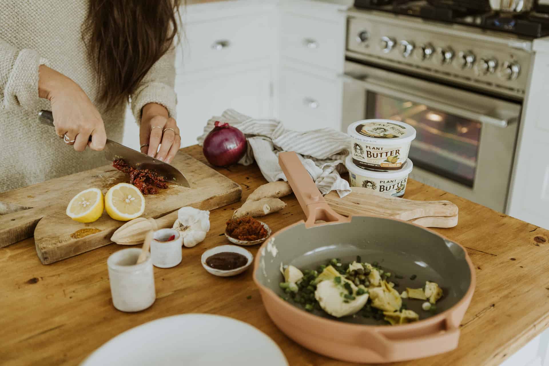 Person cutting ingredients for stuffed eggplant on a cutting board.