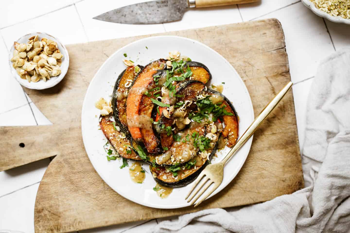 Roasted acorn squash on a white plate on a cutting board.