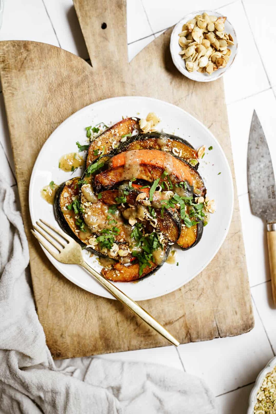 Roasted acorn squash on a white plate on a cutting board.