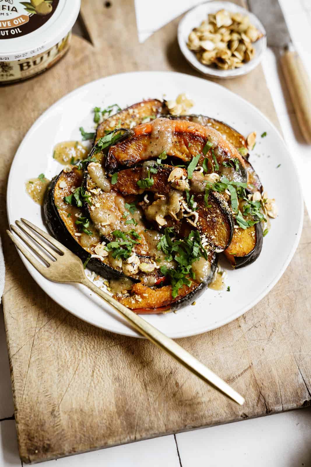 Baked acorn squash on a white plate on a cutting board.