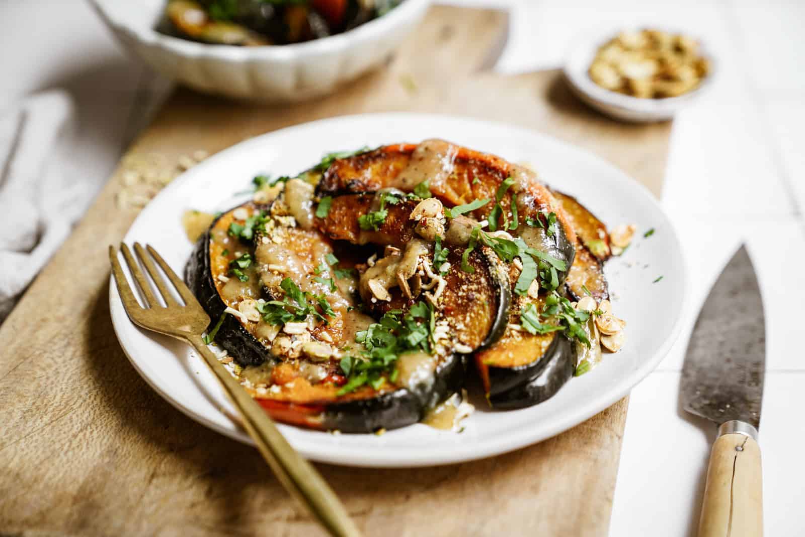 Roasted acorn squash on a white plate on a cutting board.