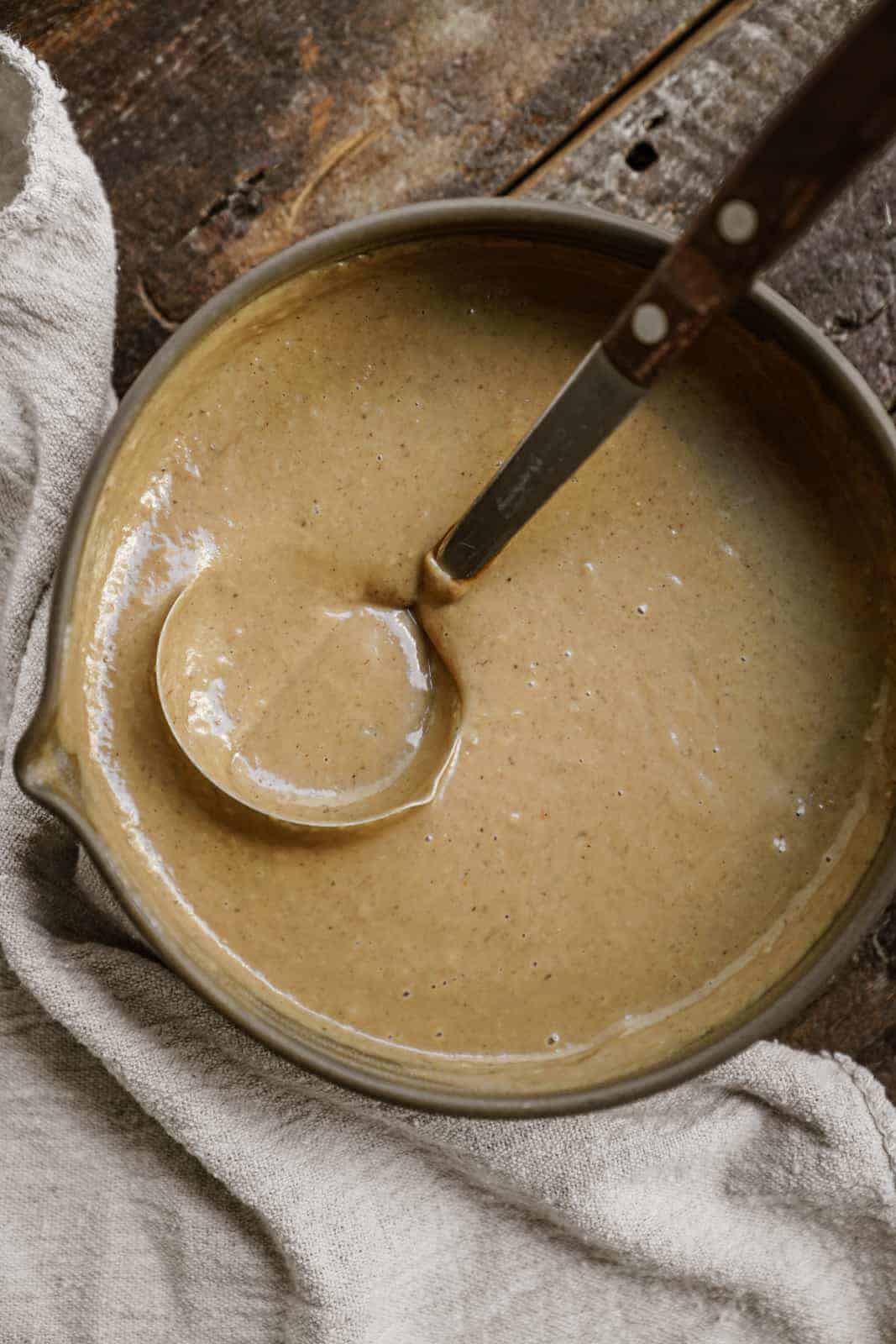 Pot of vegan gravy with ladle in it.