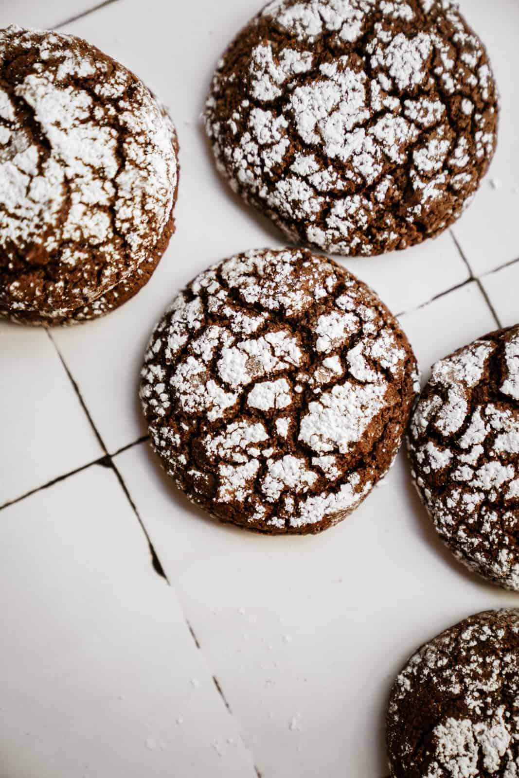 Cookies from my Chocolate Crinkle Cookie Recipe scattered on white countertop.