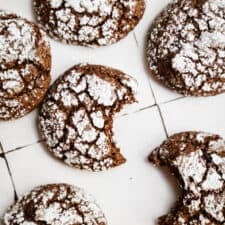 Cookies from my Chocolate Crinkle Cookie Recipe scattered on white countertop.