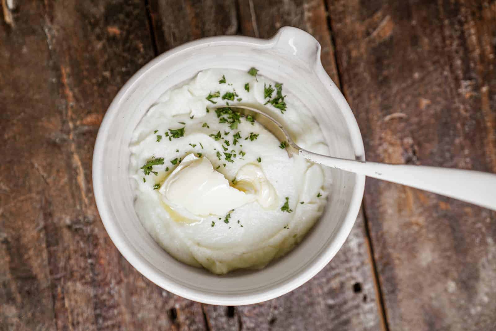 Vegan Mashed Cauliflower in a bowl with butter on top.