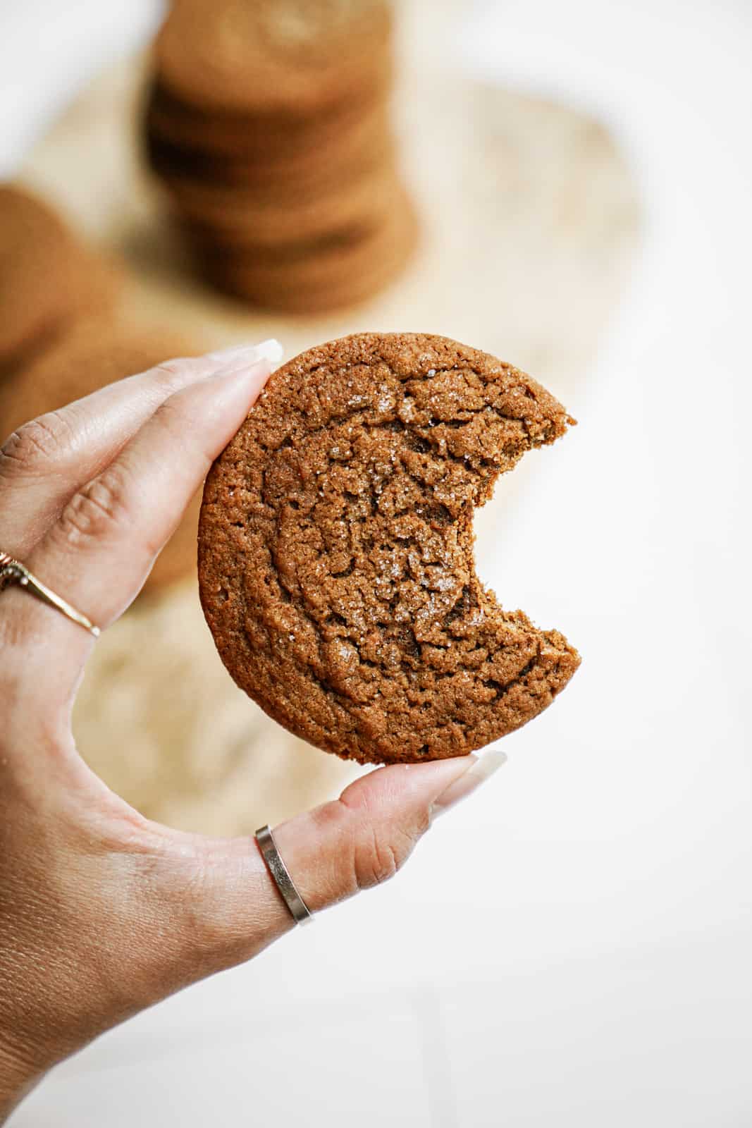 Hand holding a Vegan Ginger Snap Cookie with a bite out of it.