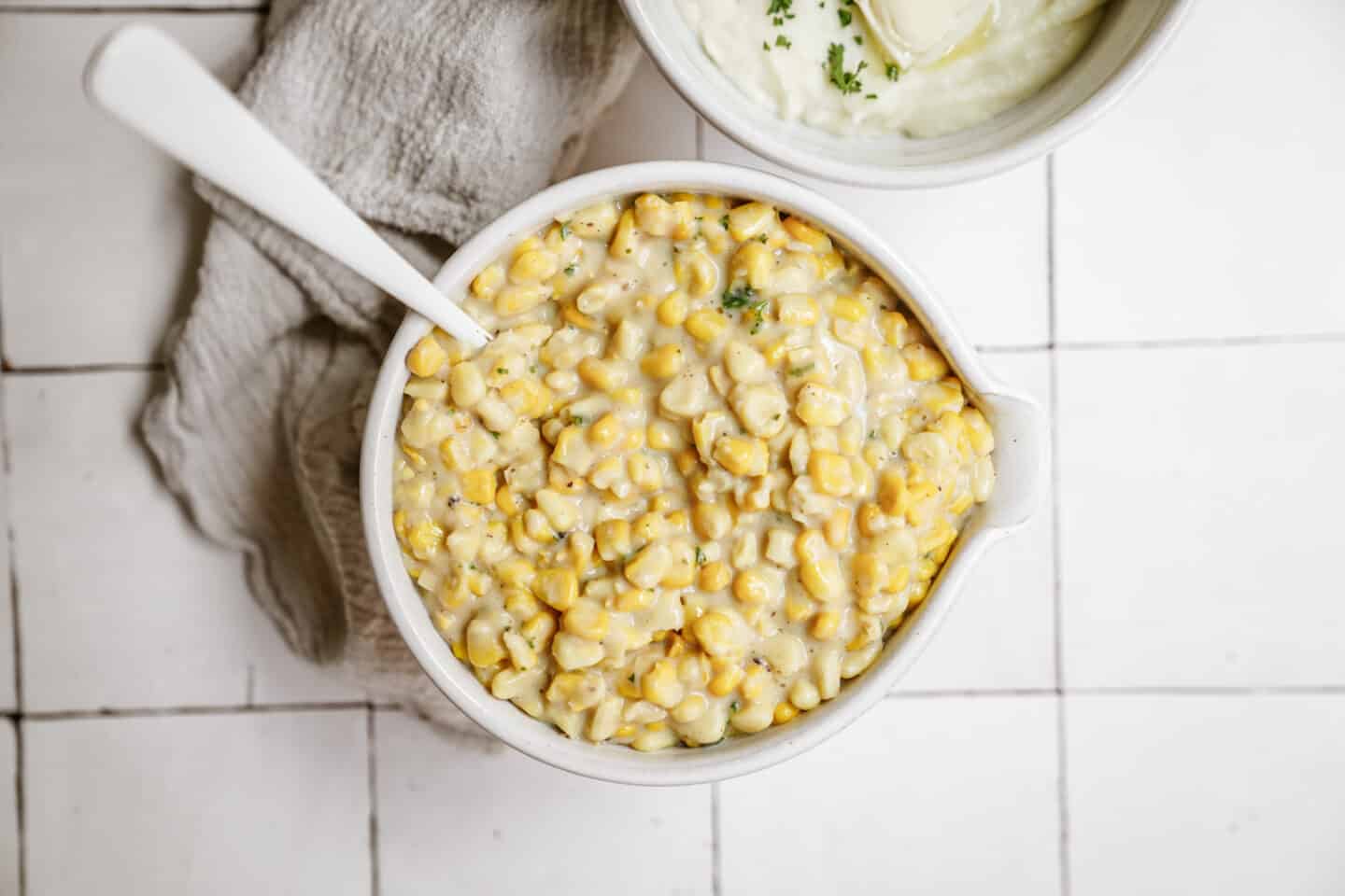 Creamed corn recipe in a serving dish on a white countertop.