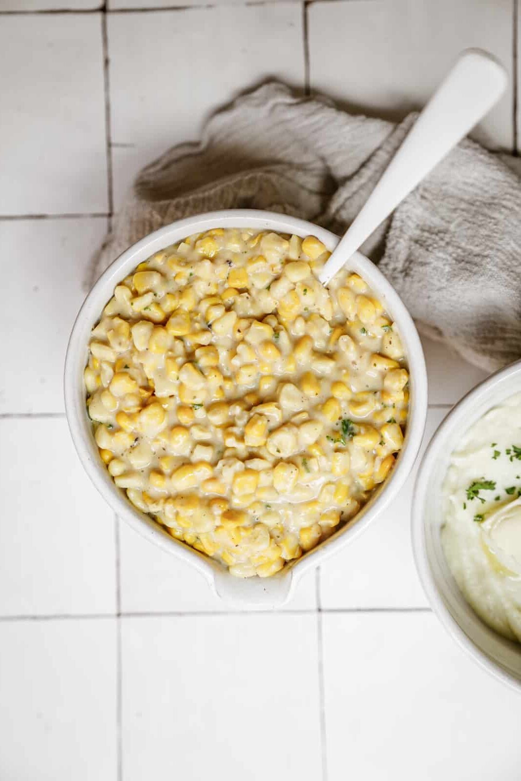 Creamed corn recipe in a serving dish on a white countertop.