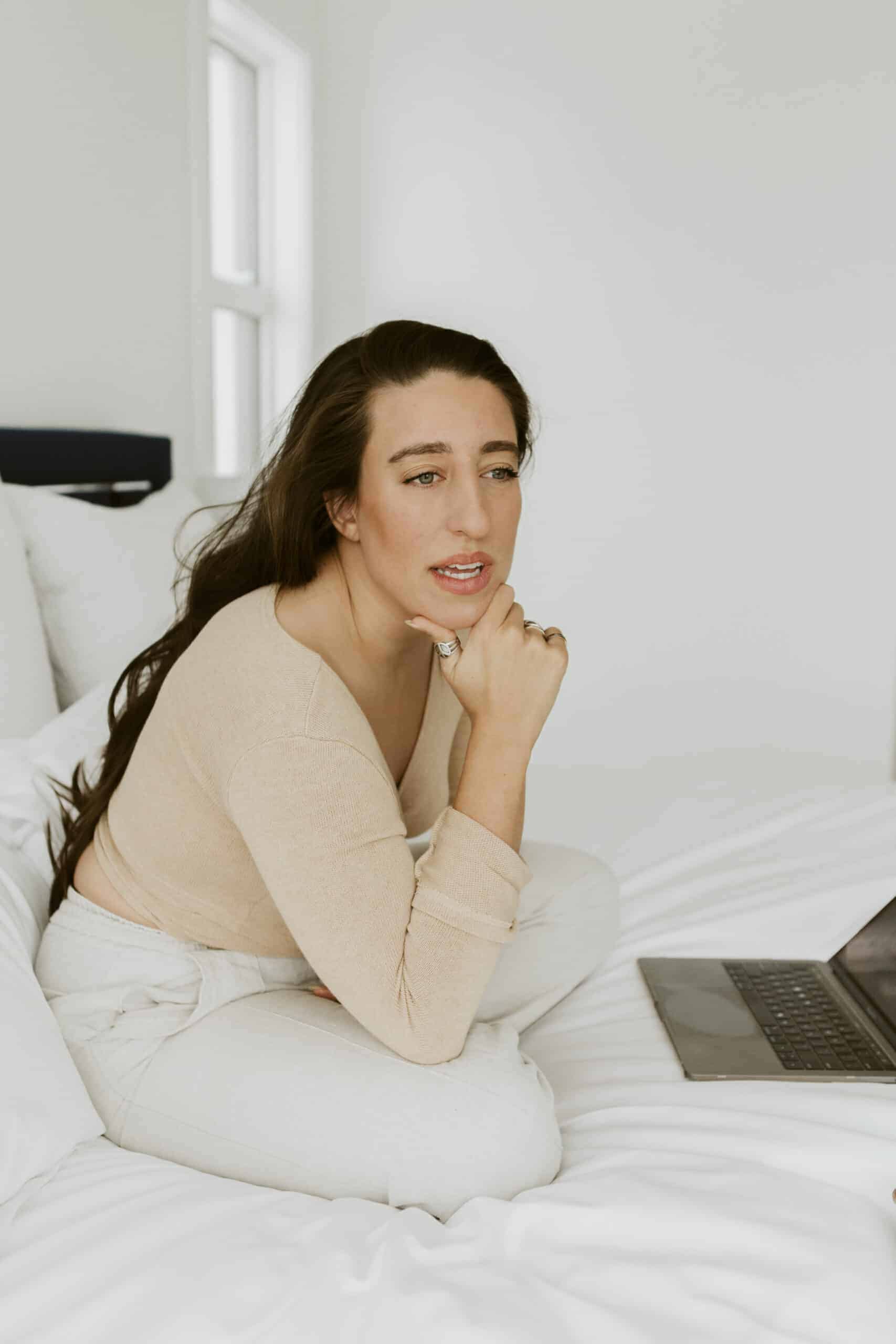 Food blogger, Maria, sitting on her bed, working at her computer.