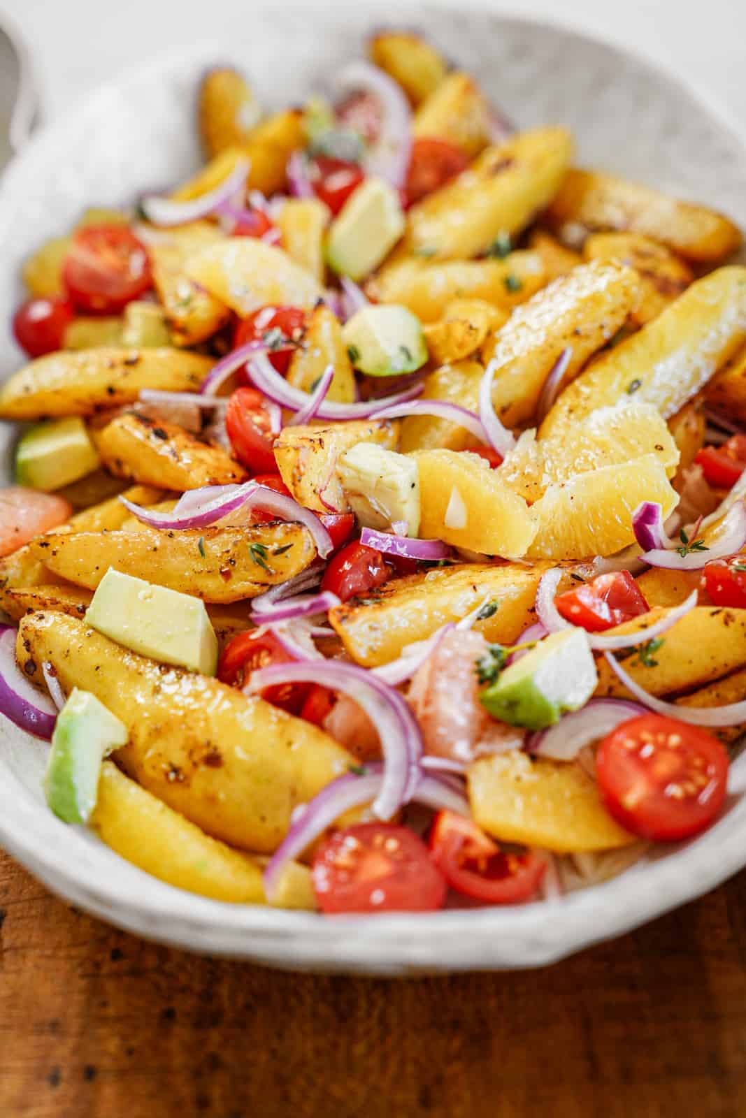 Big serving dish of vegan roasted potato salad with fresh veggies and citrus flavor.