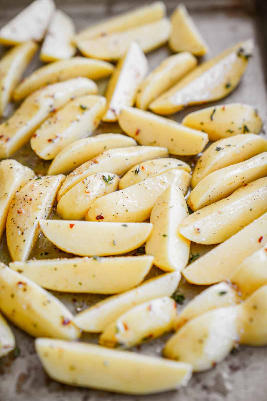 Raw, seasoned potatoes on a baking sheet, ready to be baked for easy roasted potato salad.