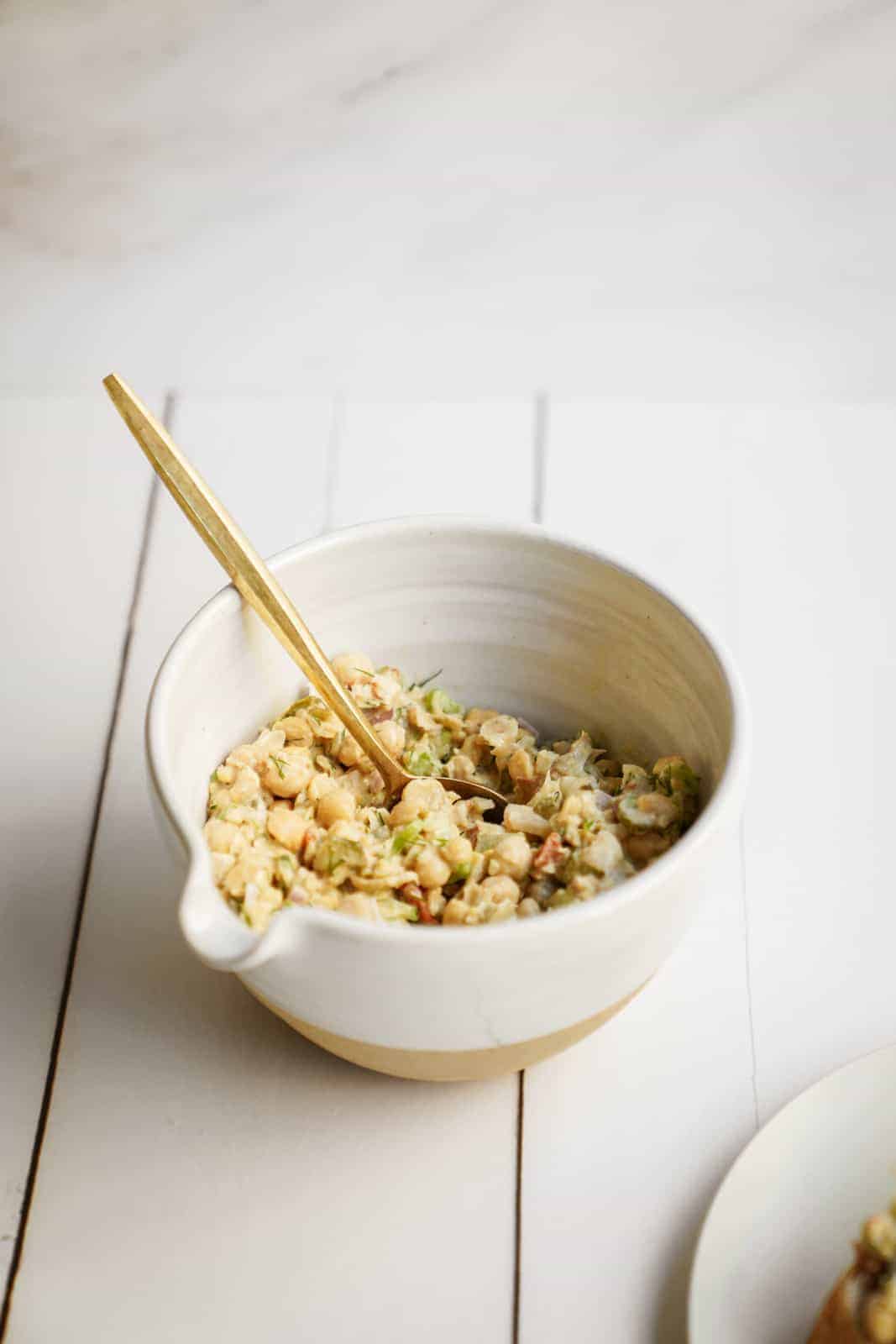 A big bowl of Mashed Chickpea Salad with a serving spoon