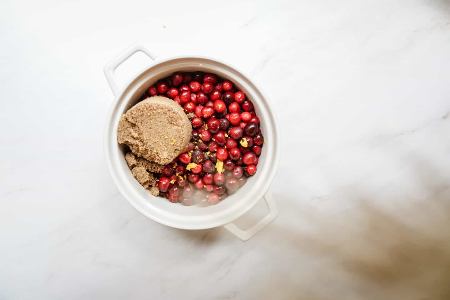 Sugar added to pot of fresh cranberries for vegan cranberry sauce