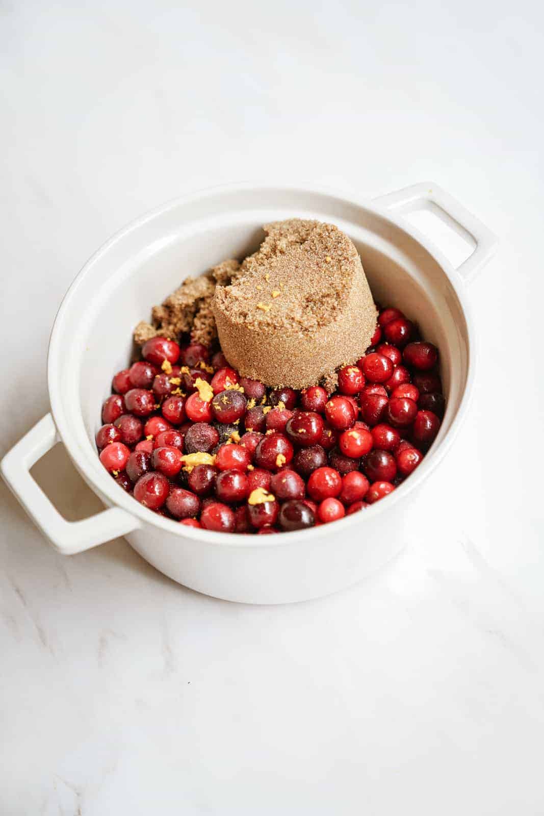 Sugar added to pot of fresh cranberries for vegan cranberry sauce