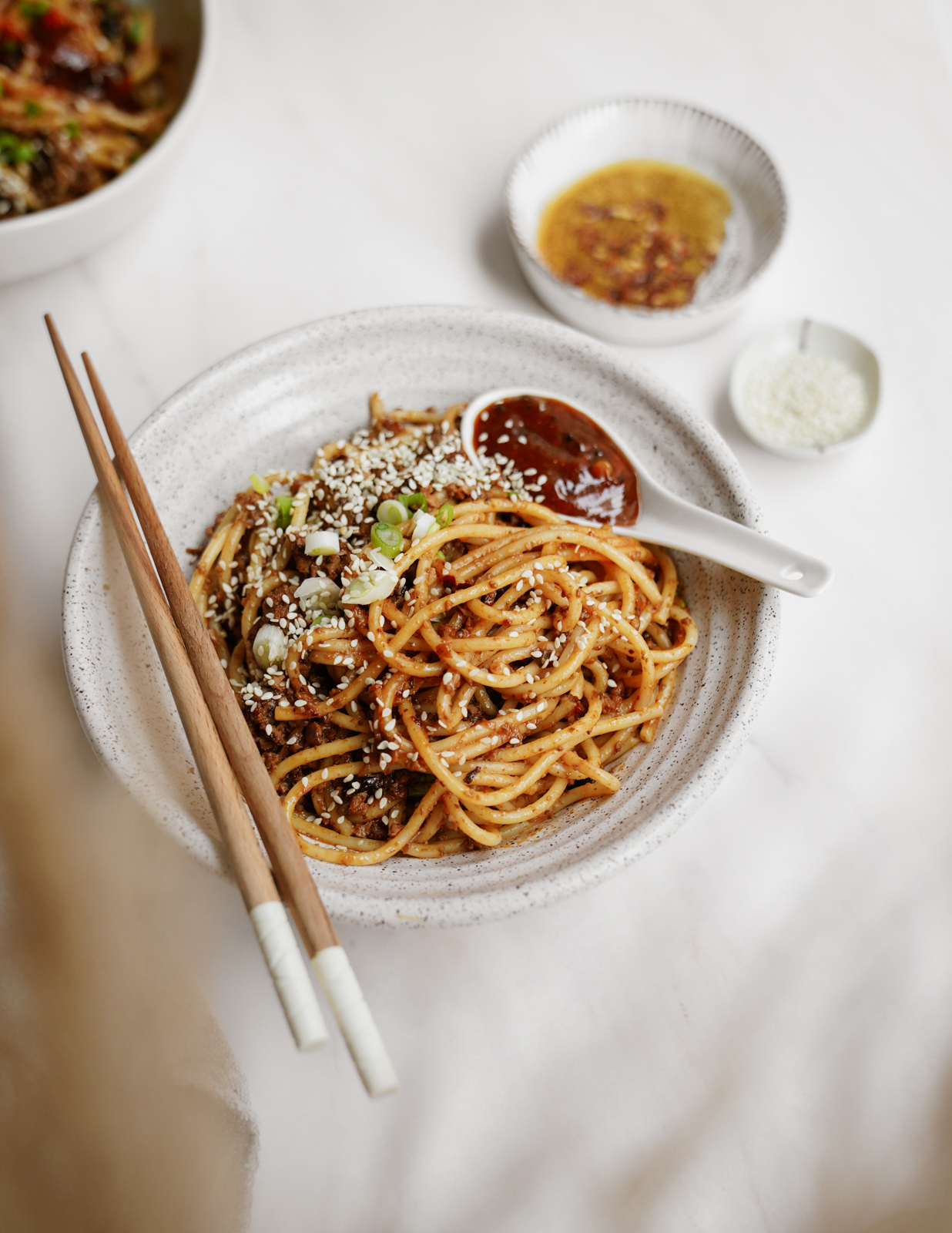 Vegan dan dan noodles in a white bowl with chopsticks.