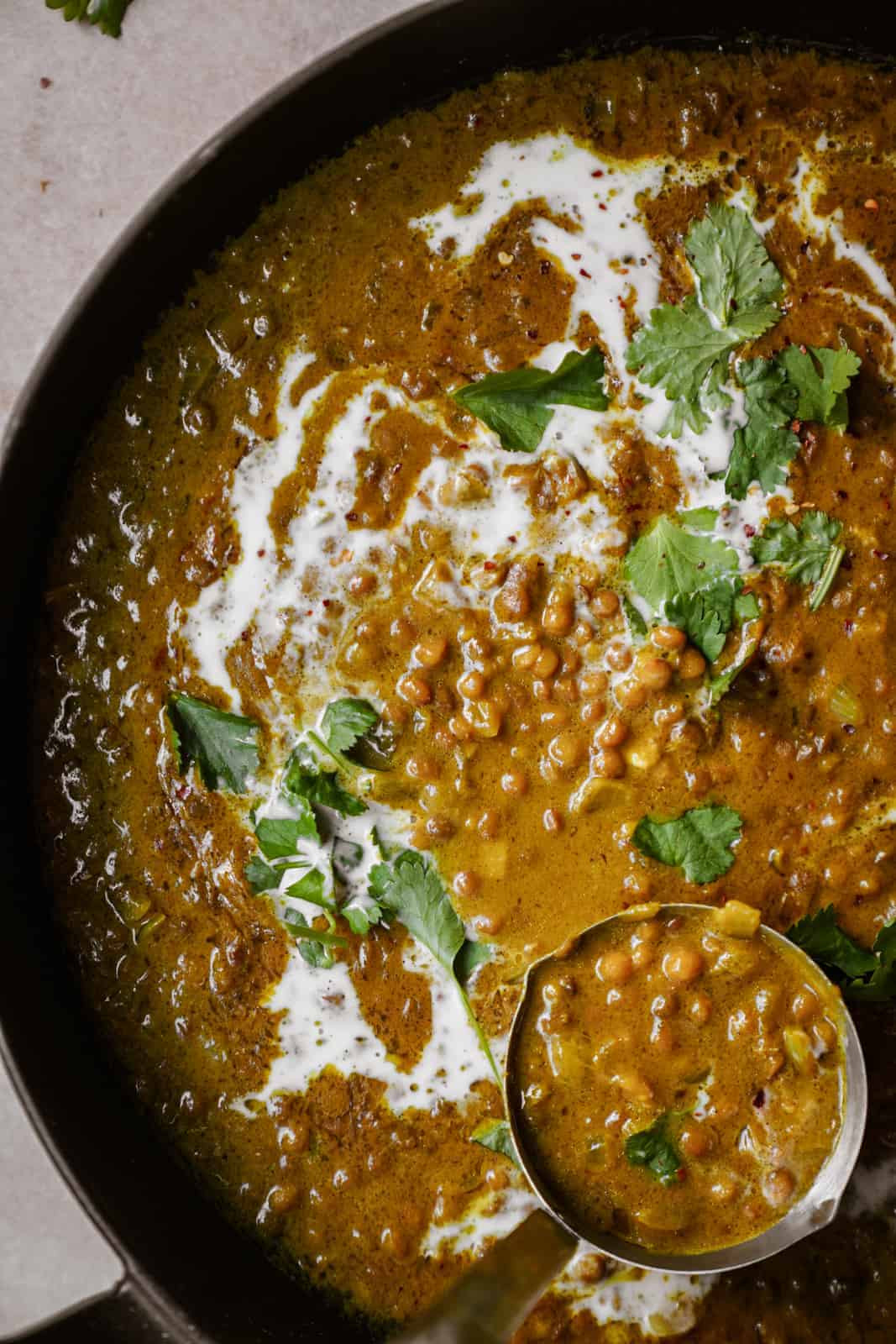 Green Lentil Curry in a serving dish with a serving spoon.