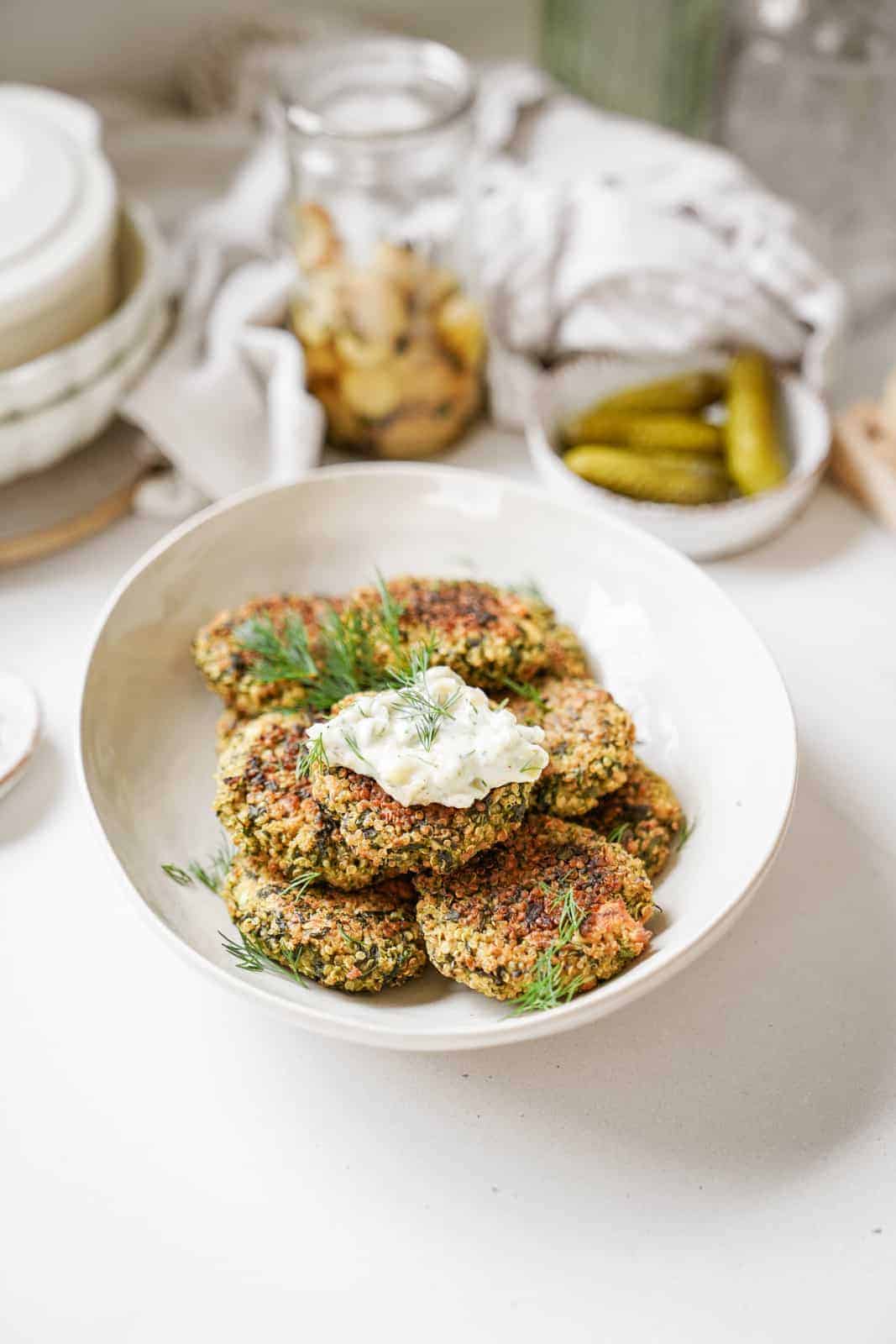 Quinoa and Spinach Patties on serving dish on countertop surrounded by ingredients.